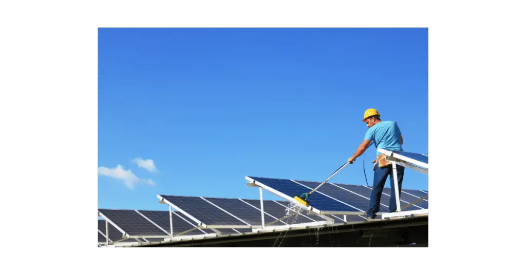 Maintenance man cleaning solar panels on a roof