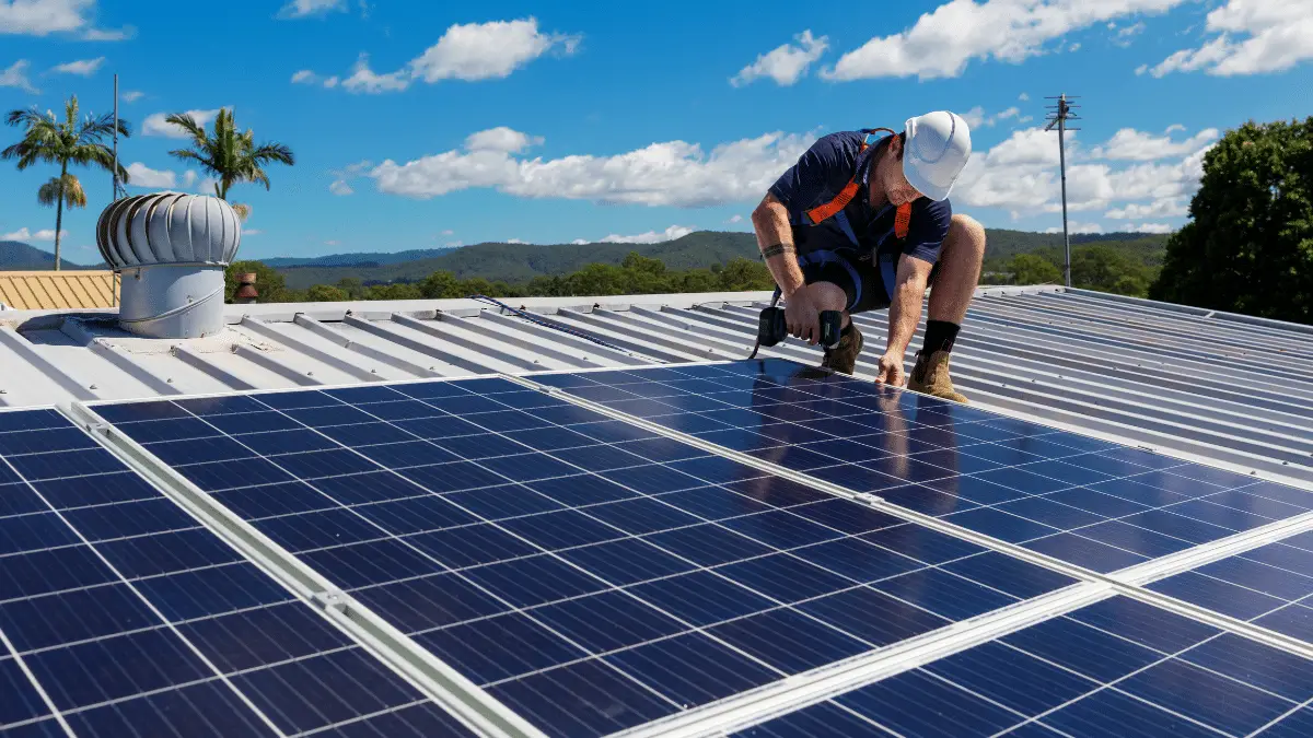 Installer with drill on roof to install photovoltaic cells