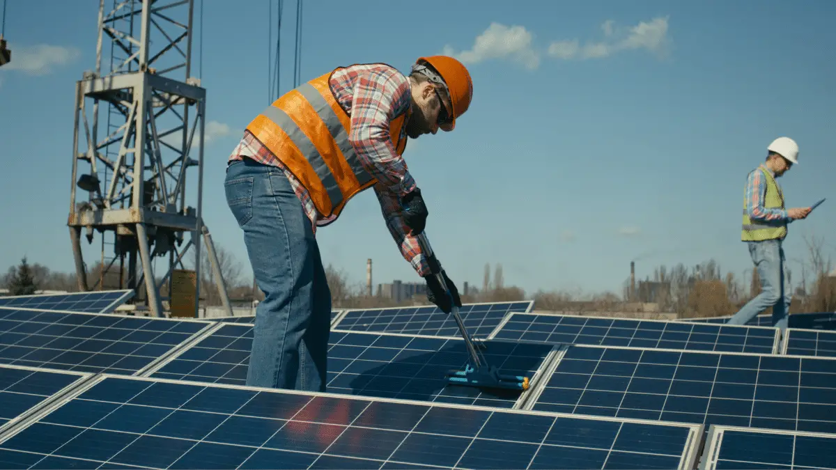 Technician cleaning solar panels on flat roof