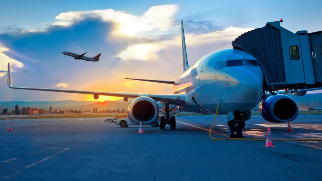 Plane taking off at airport with sun setting in horizon