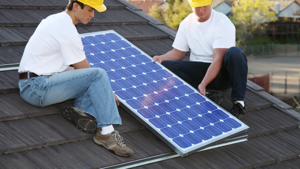 Two Men Install Solar Panels On A Roof